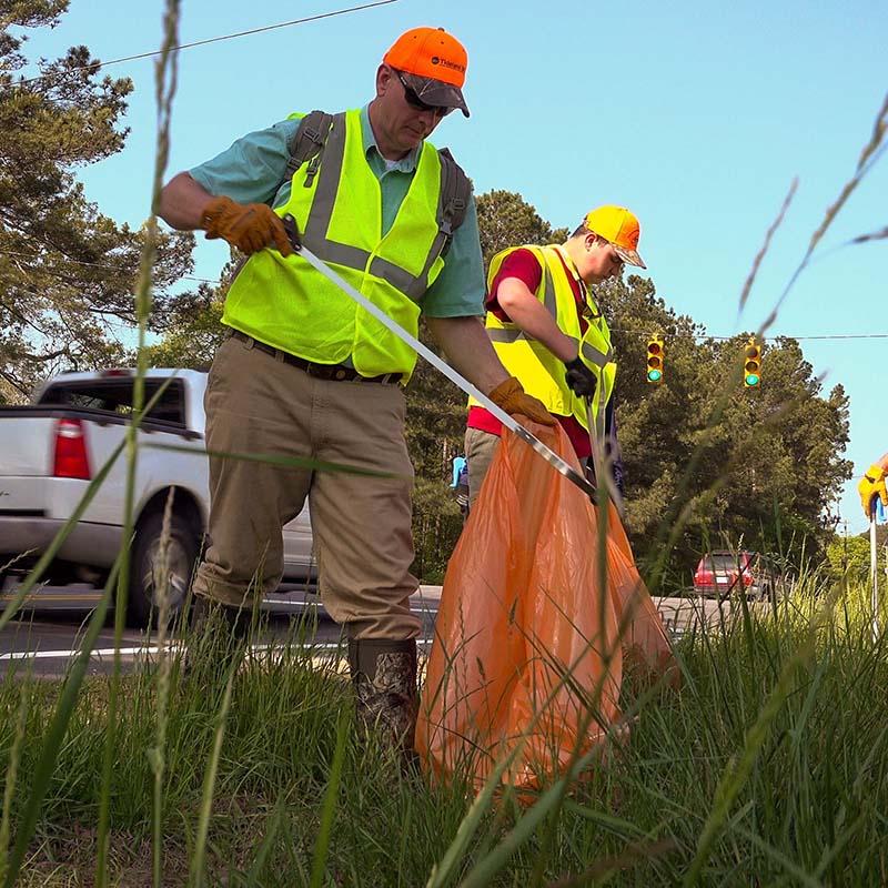 two people using grabbers to pick up litter
