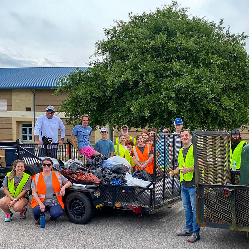 volunteers with a trailer full of collected trash bags