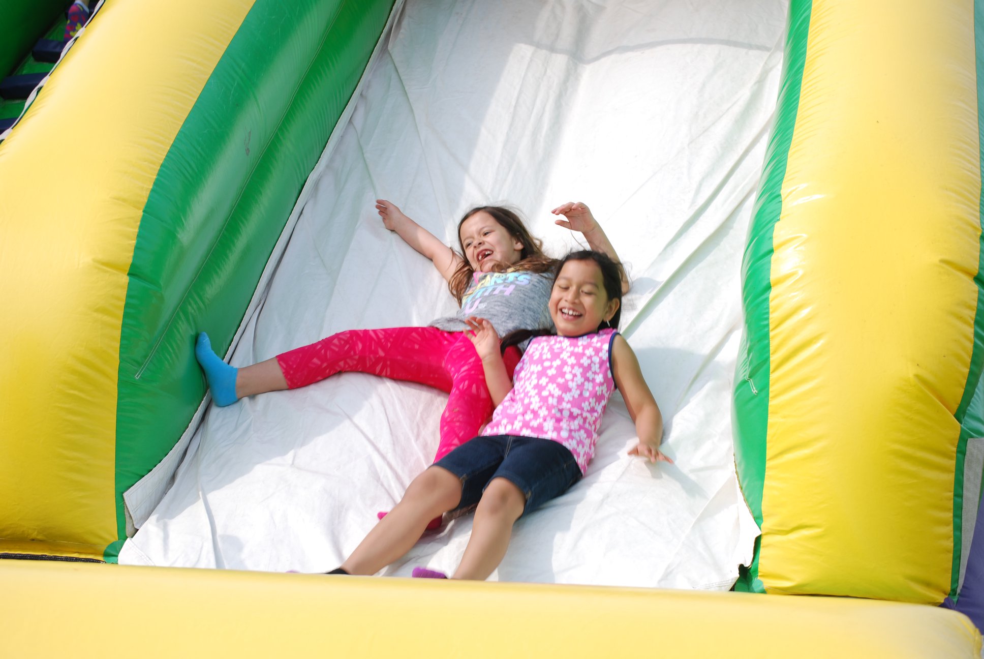 Children at Community Day, sliding down a blow-up slide