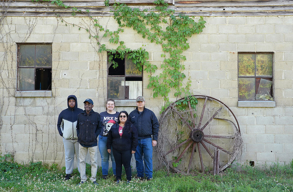 Participating students pose in front of an old farm building
