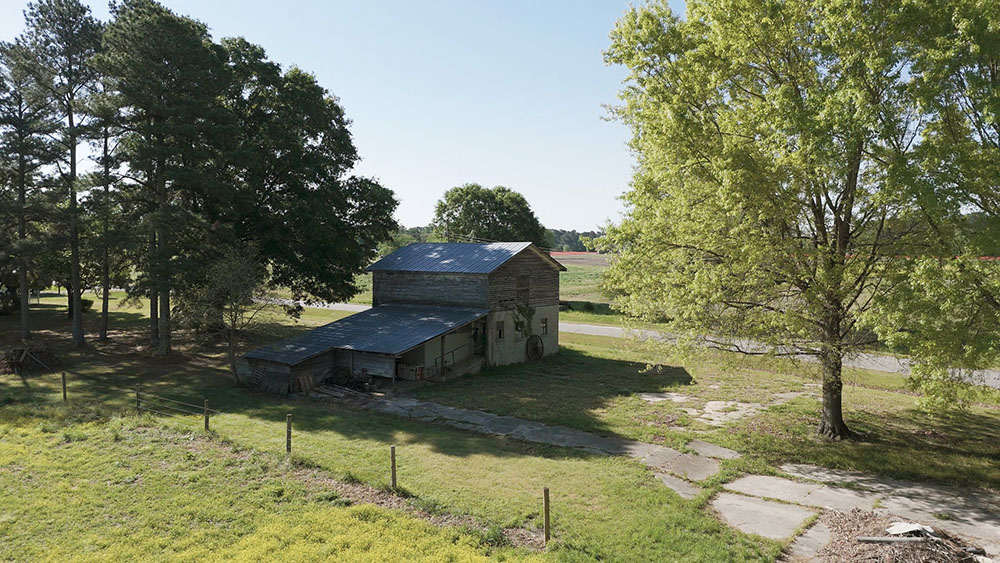 Wide shot of the old farm building in an lush, sunny landscape