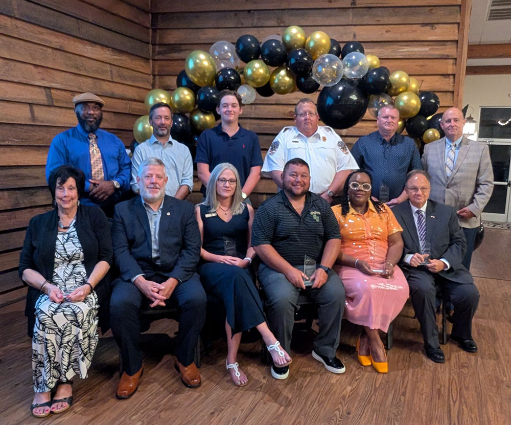 Photo of various community members, including Craig Olive, in front of a balloon arch.
